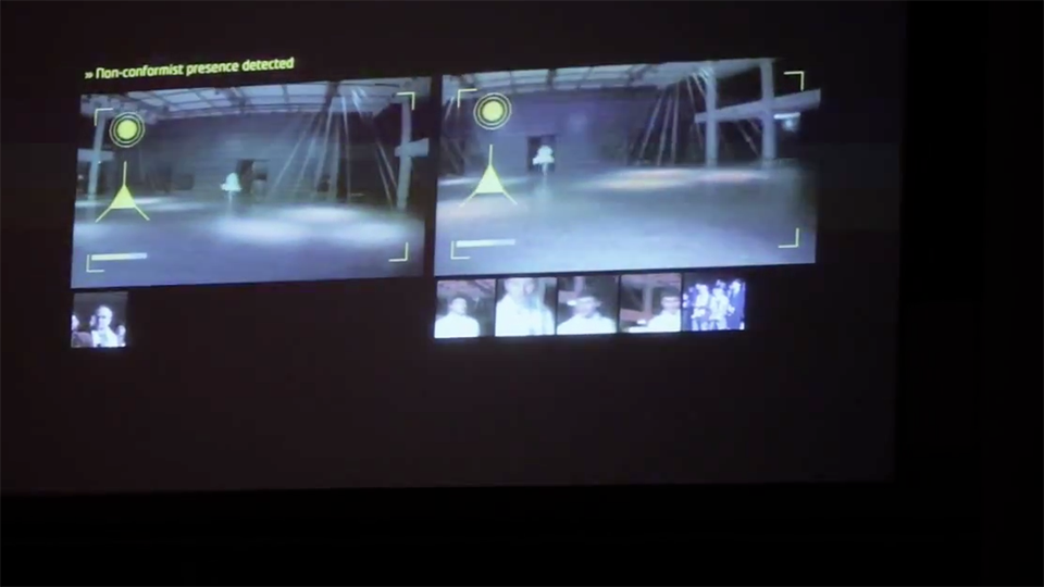 Video still: dual surveillance-style screens displaying camera feeds of a runway with the overlay text Non-conformist presence detected