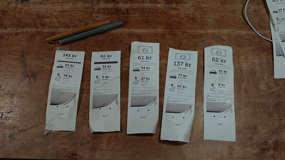 Five narrow taxi-style receipt printouts laid out on a wooden table next to a pencil, each showing a trip cost