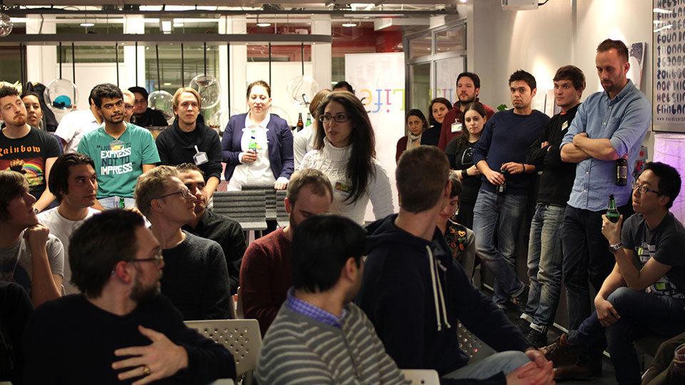 Crowd of attendees seated and standing at the Mobile Life venue, listening as a speaker holds the floor