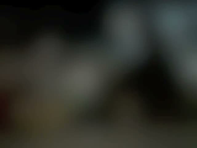 Video still: a dimly lit bar scene, mostly dark with faint silhouettes and warm highlights